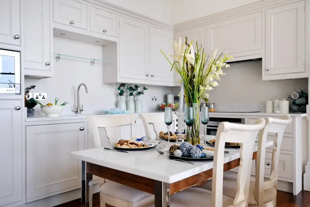 Handmade kitchen in Worthing with marble-top dining table, white shaker cabinetry and integrated appliances