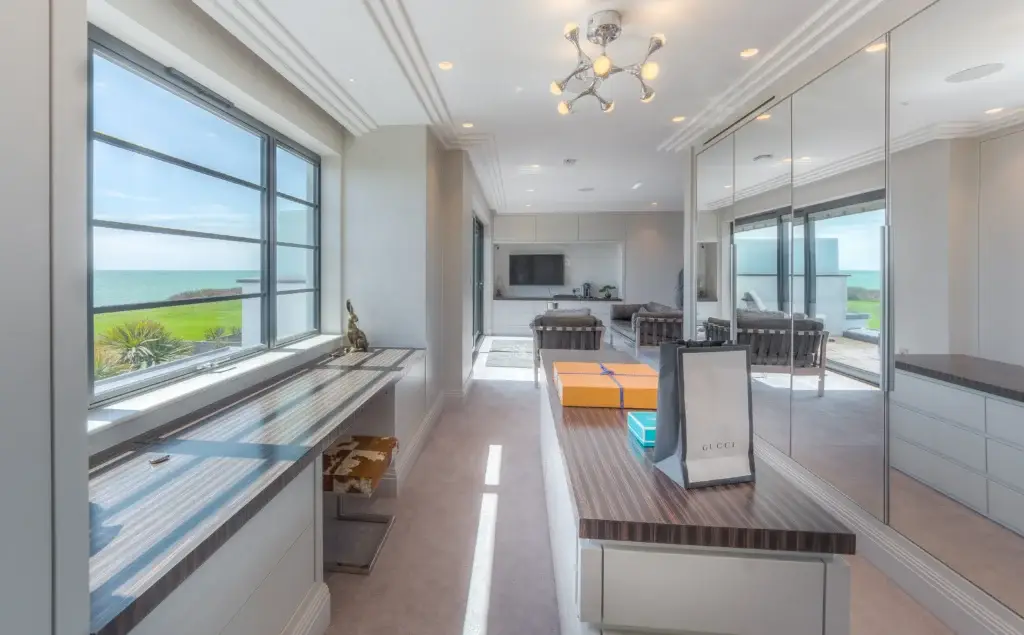 Bespoke dressing room with mirrored wardrobes, coastal view, and custom cabinetry, part of a handmade Worthing interior.