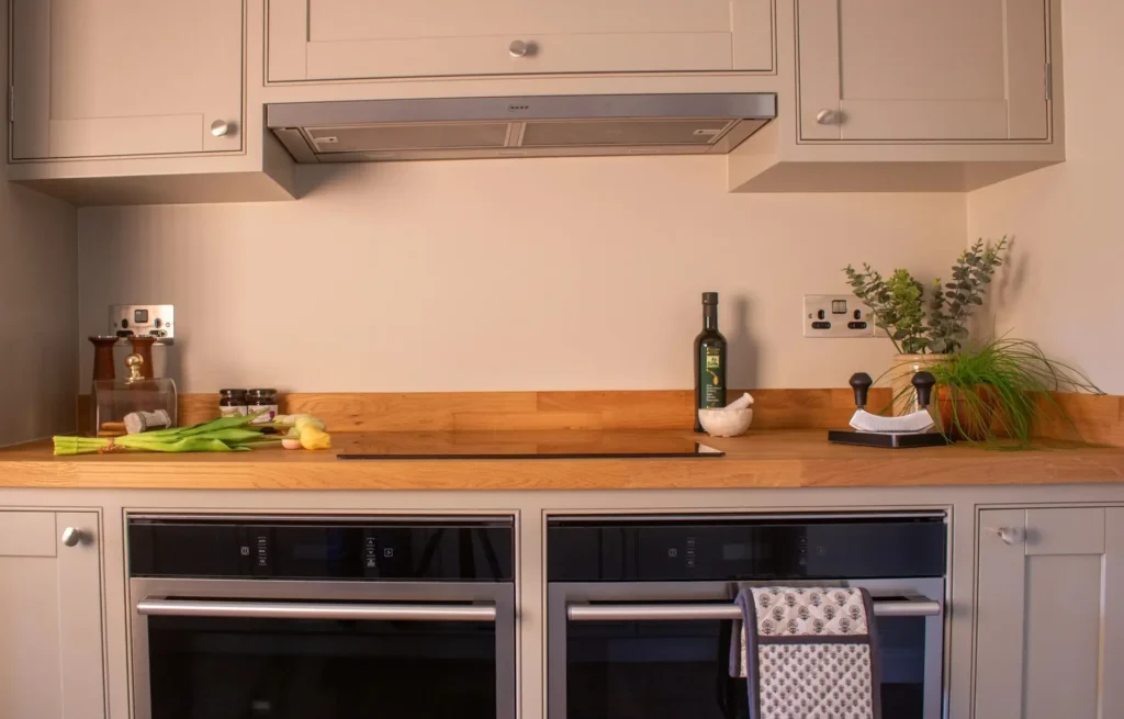 Handmade kitchen in Worthing with integrated double ovens, oak worktop and contemporary neutral cabinetry